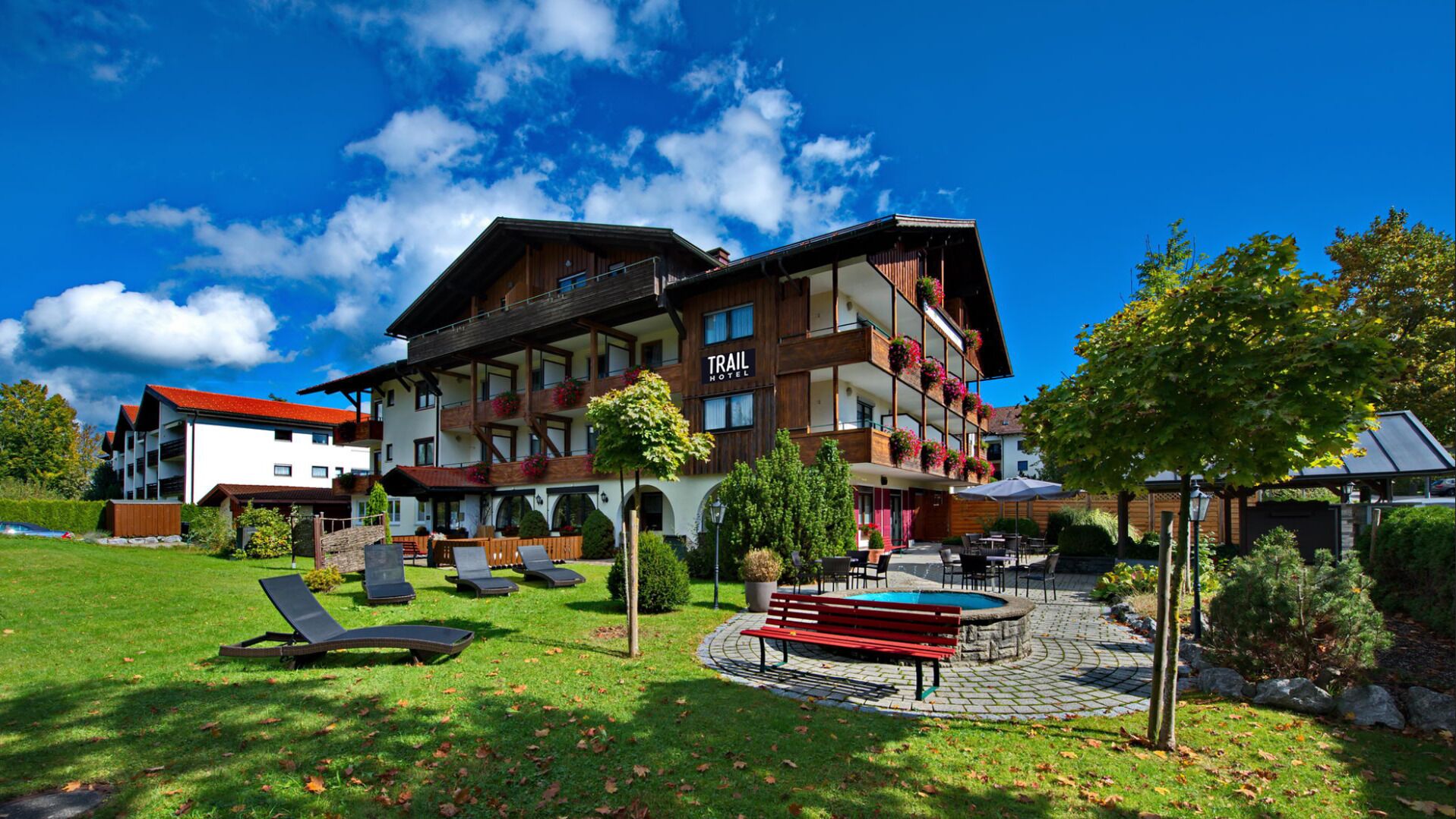Ein Hotel mit Pool, Liegestühlen und einem Gartenbereich.