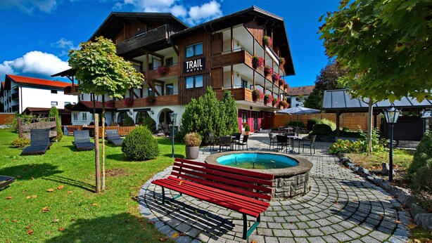 Ein Hotel mit Pool, Außenbereich und einer roten Bank.