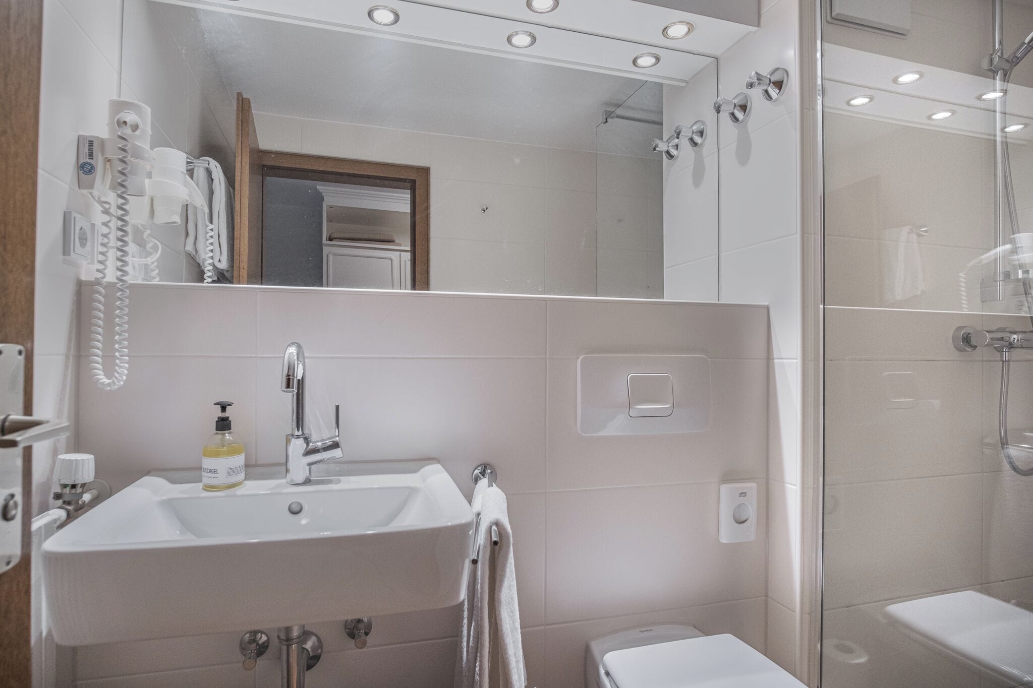 Ein modernes Badezimmer mit Waschbecken, Spiegel und Dusche.