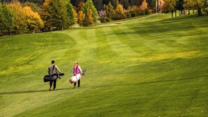 Un terrain de golf où l’on voit une personne portant un sac de golf et une autre personne qui marche à côté d’elle.