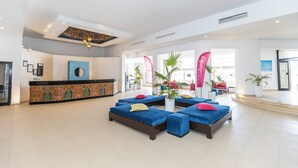 A spacious lobby with a reception desk, blue cushioned seating areas, and potted plants. - Le Petit Palais Djerba & Spa (Djerba Midun)