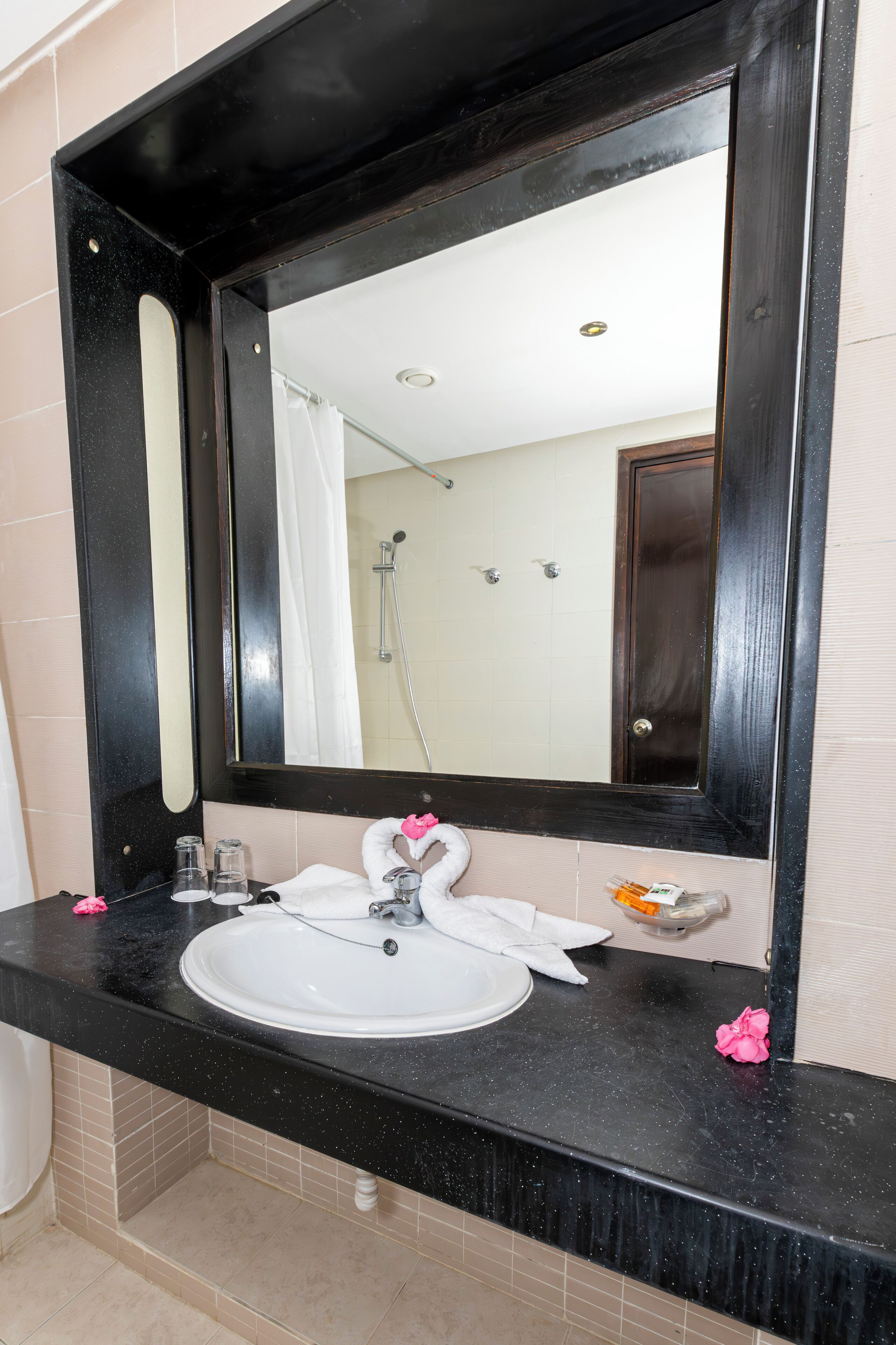 A bathroom with a black countertop, white sink, and a large mirror.