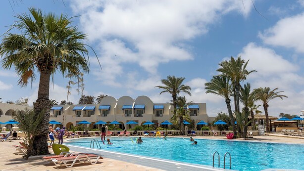 A pool area with palm trees, lounge chairs, and umbrellas. - Le Petit Palais Djerba & Spa (Djerba Midun)