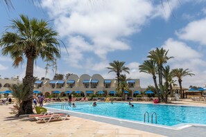 A pool area with palm trees, lounge chairs, and umbrellas. - Le Petit Palais Djerba & Spa (Djerba Midun)