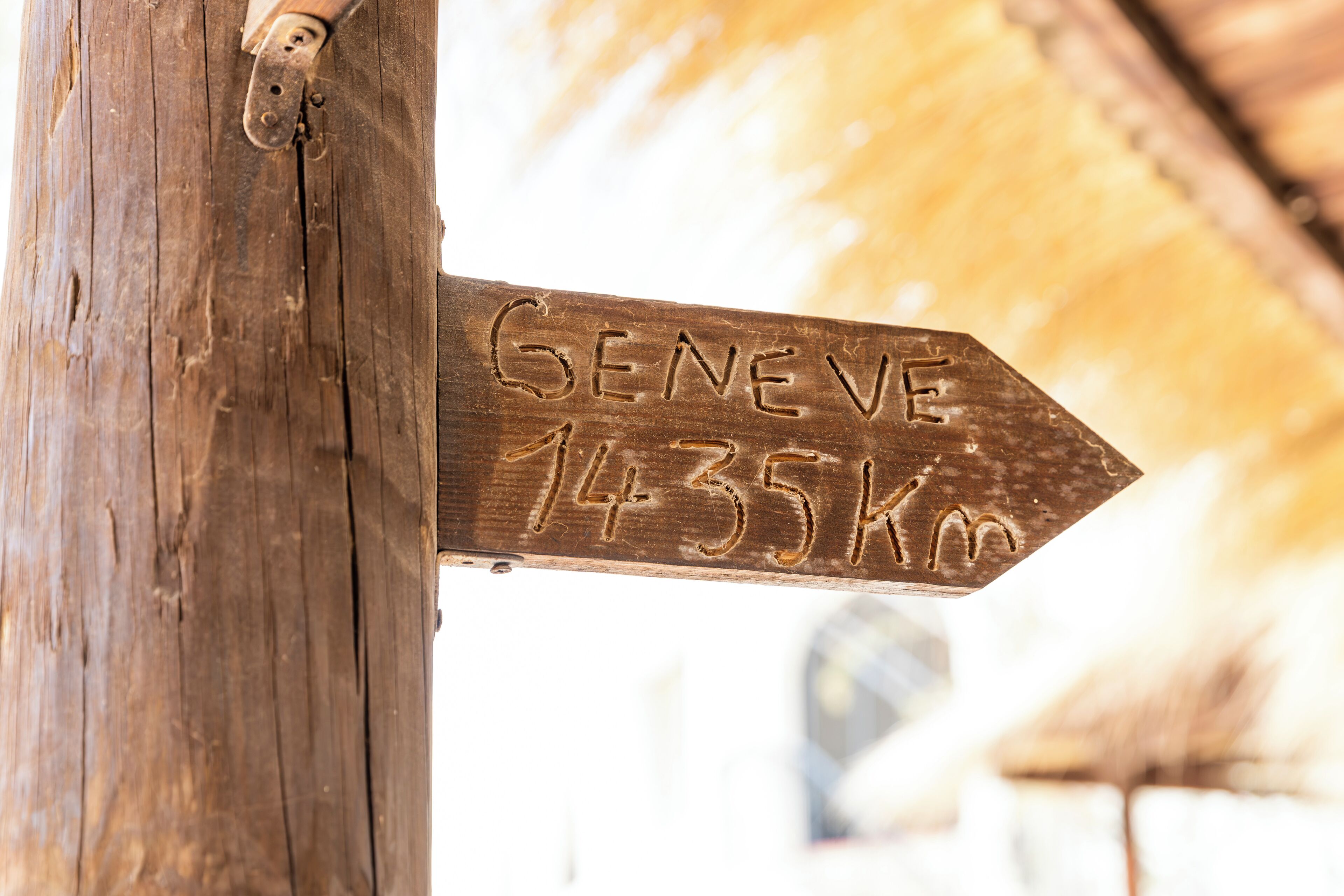 Een houten bord met de tekst 'GENEVE 1435 km' gegraveerd.
