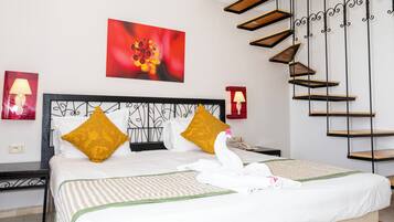 Una habitación de hotel con una cama, una escalera y un cuadro de una flor roja en la pared.