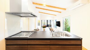 A modern kitchen with a central island, wooden beams, a large window, and a built-in TV.