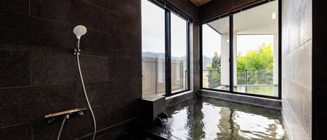 A modern bathroom with a glass-enclosed hot tub, large windows, and a shower area.