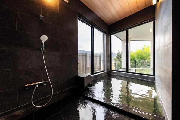 A modern bathroom with a glass-enclosed hot tub, large windows, and a shower area.