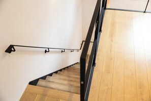 A wooden staircase with black handrails and a white wall. - TERRA Yufuin (Yufu)