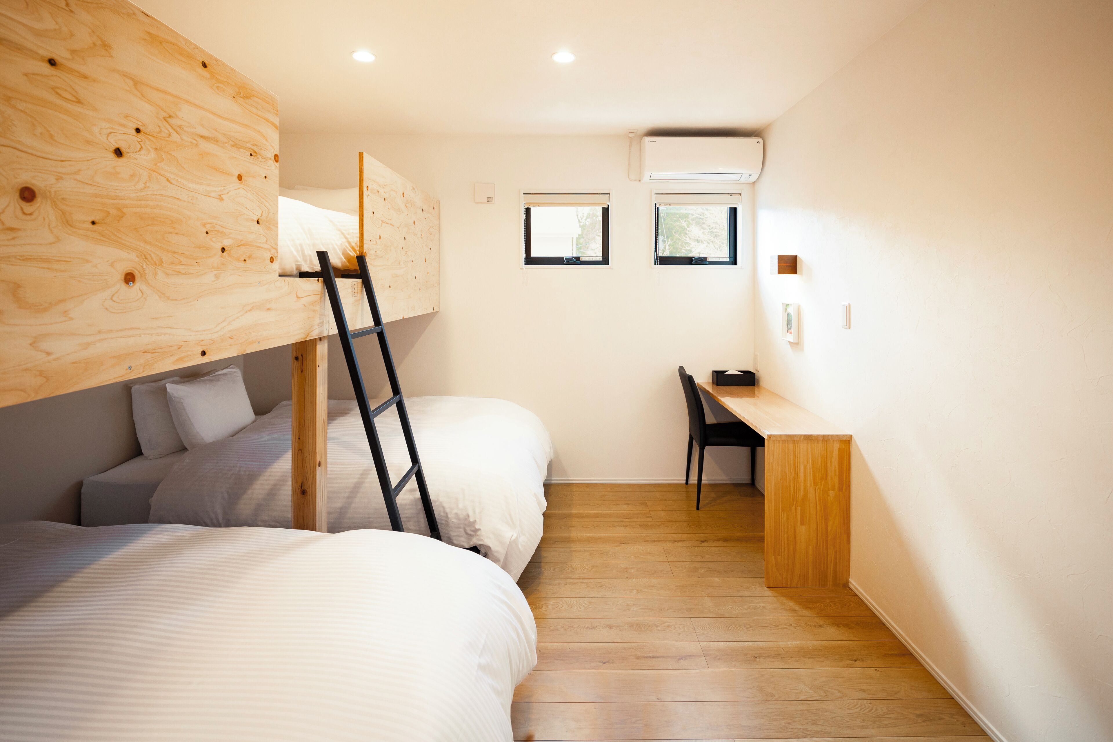 A compact room with two bunk beds, a desk, and a chair.