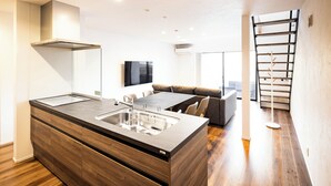 A modern kitchen with a central island, built-in appliances, and a dining area with a sofa and table.