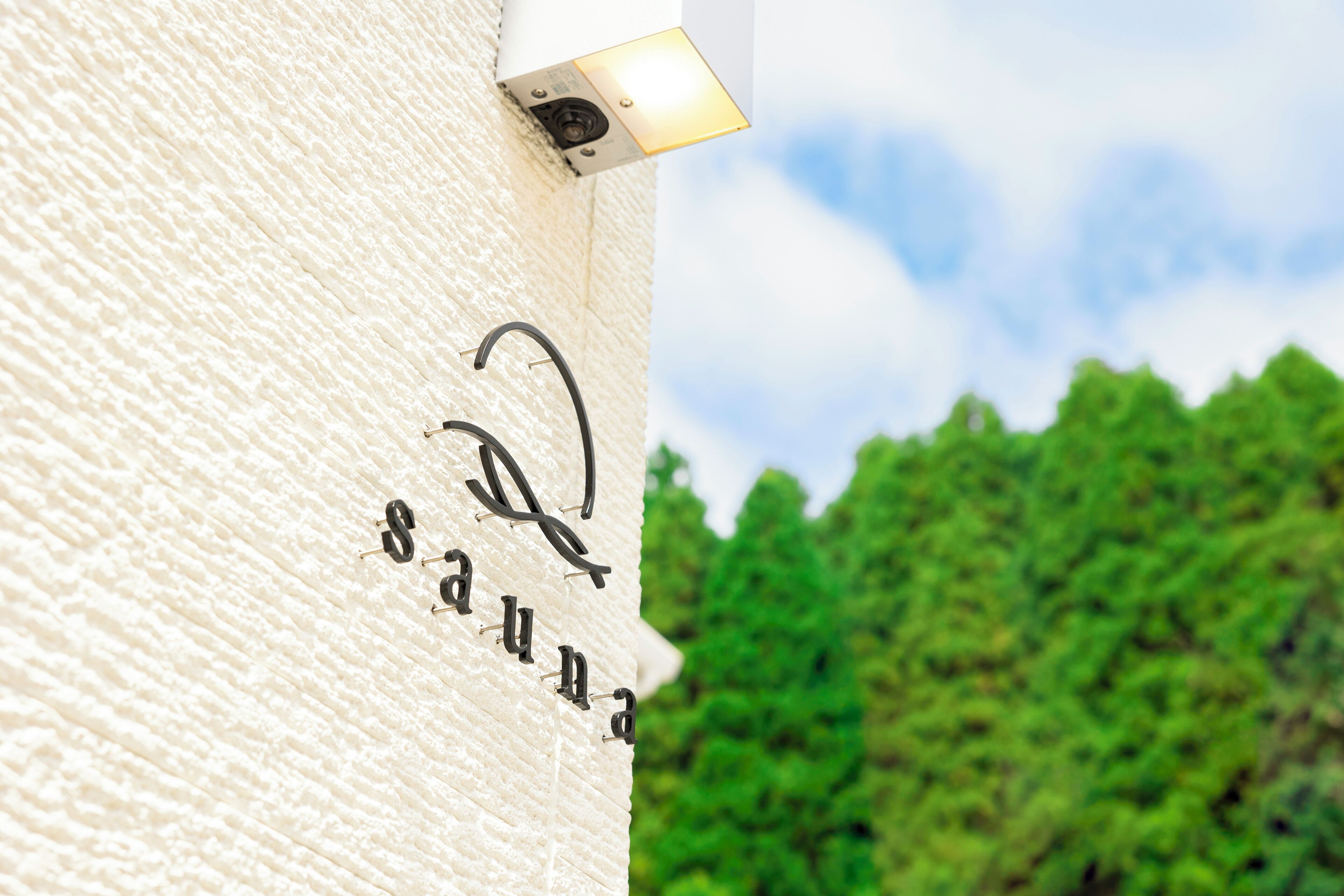 A textured wall with the words "Sauna" and a stylized "S" logo.