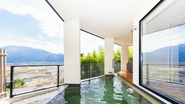 A modern infinity pool with a clear view of the mountains, a glass railing, and a minimalist design.