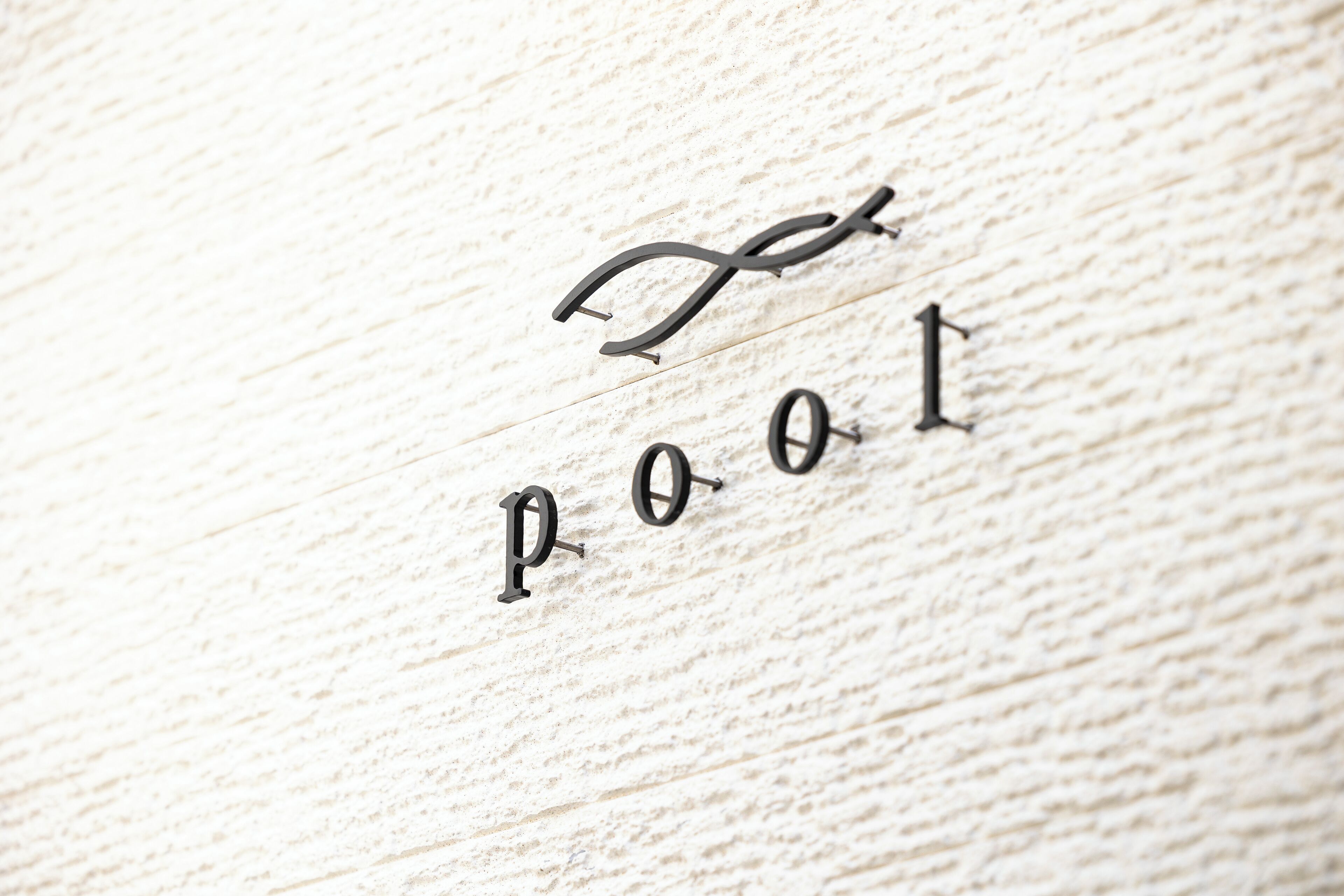 Close-up de uma superfície de madeira com as letras "P O O L" dispostas de forma estilizada.
