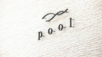 Close-up de uma superfície de madeira com as letras "P O O L" dispostas de forma estilizada.
