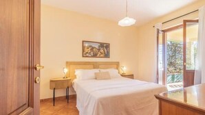 A bedroom with a bed, bedside tables, a painting on the wall, and a view through a glass door. - Modern and spacious for an unforgettable stay
 (Lazio)
