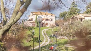 A large, two-story building with a tiled roof and arched windows, surrounded by a well-maintained garden and a winding path. - Modern and spacious for an unforgettable stay
 (Lazio)