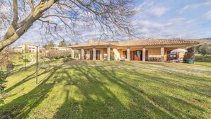 A two-story building with a tiled roof, a covered patio, and a well-maintained lawn. - Modern and spacious for an unforgettable stay
 (Lazio)