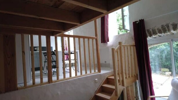Una escalera de madera que conduce a un balcón con vistas a zonas verdes.