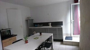 Una cocina compacta con microondas, un refrigerador pequeño y una mesa de comedor con sillas.