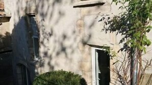 Un edificio de fachada de piedra, una ventana y una canaleta de metal.