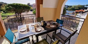 Un balcon avec une table dressée pour le dîner, donnant sur une rivière et un parc.