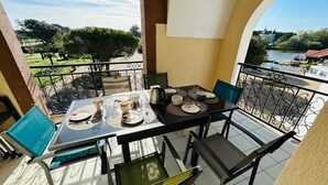 Ein Balkon mit Esstisch, Stühlen und Blick auf einen Fluss und eine Burg.