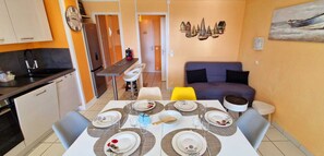 Un espacio habitable compacto con comedor, kitchenette y sofá.