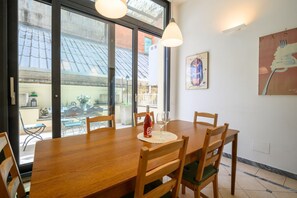 A dining area with a wooden table and chairs, a bottle of water, and a glass. - Quattro Cantoni Apartment Monti (Roma)