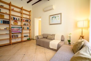 A living room with a sofa, a bookshelf, a television, and a lamp. - Quattro Cantoni Apartment Monti (Roma)