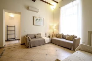 A living room with two sofas, a lamp, a painting, and a ladder. - Quattro Cantoni Apartment Monti (Roma)