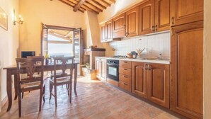 A kitchen with wooden cabinets, a dining table with chairs, and a view through an open door. - Comfort and attention to detail for an exceptional stay
 (Lazio)