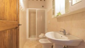 A bathroom with a wooden door, a shower, a sink, and a mirror. - Comfort and attention to detail for an exceptional stay
 (Lazio)