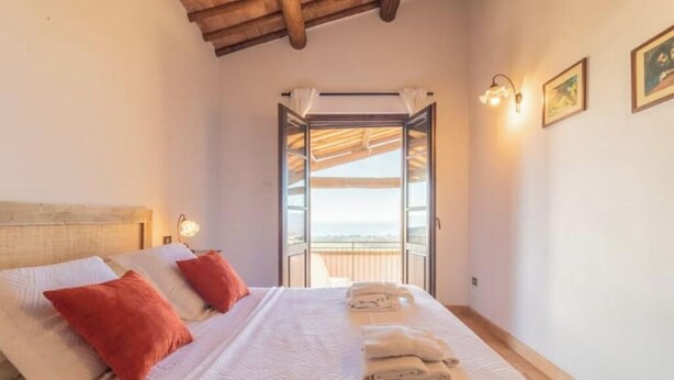 A bedroom with a bed, pillows, a nightstand, a window with curtains, and a view of the outside. - Comfort and attention to detail for an exceptional stay
 (Lazio)