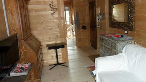 A wooden interior with a white sofa, a wooden cabinet, and a small table. - Villa 5 Torri  (Cortina d´Ampezzo)
