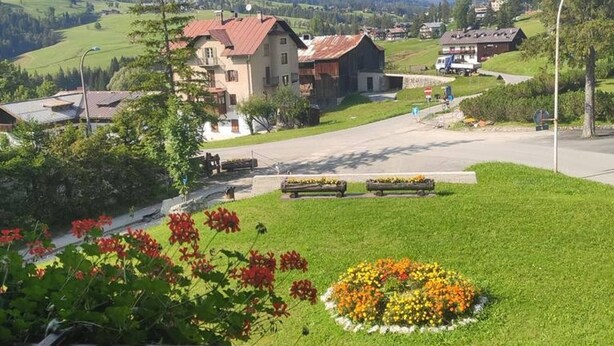 A mountain village with traditional houses, a well-maintained lawn, and a clear view of the surrounding mountains. - Villa 5 Torri  (Cortina d´Ampezzo)