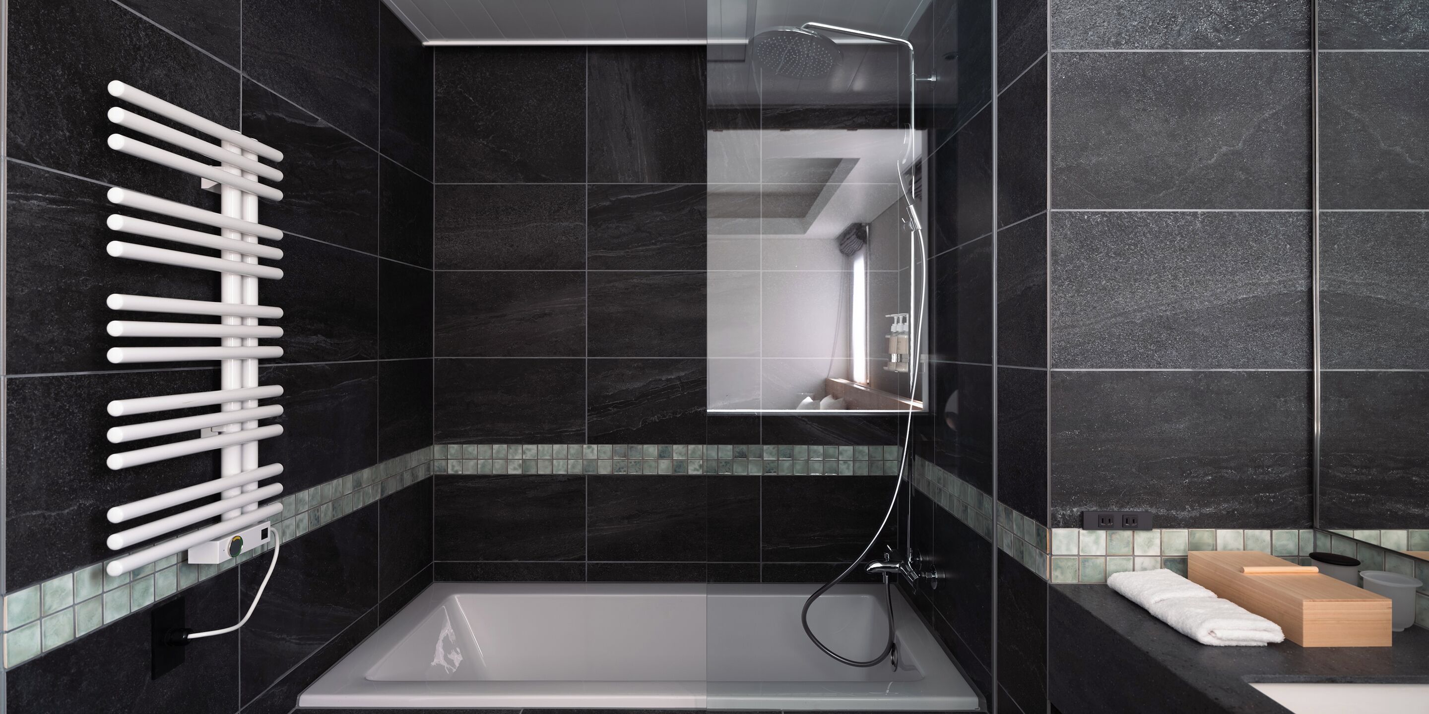 A modern bathroom with a bathtub, a towel rack, and a mirror.
