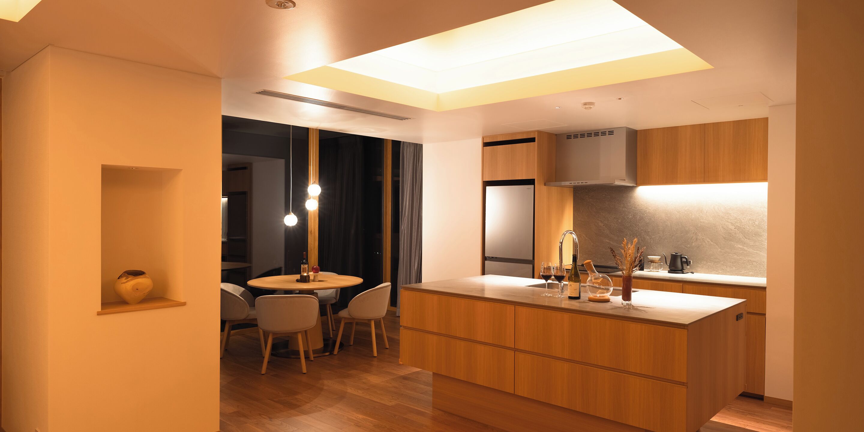 A modern kitchen with wooden cabinets, a central island, and pendant lighting.