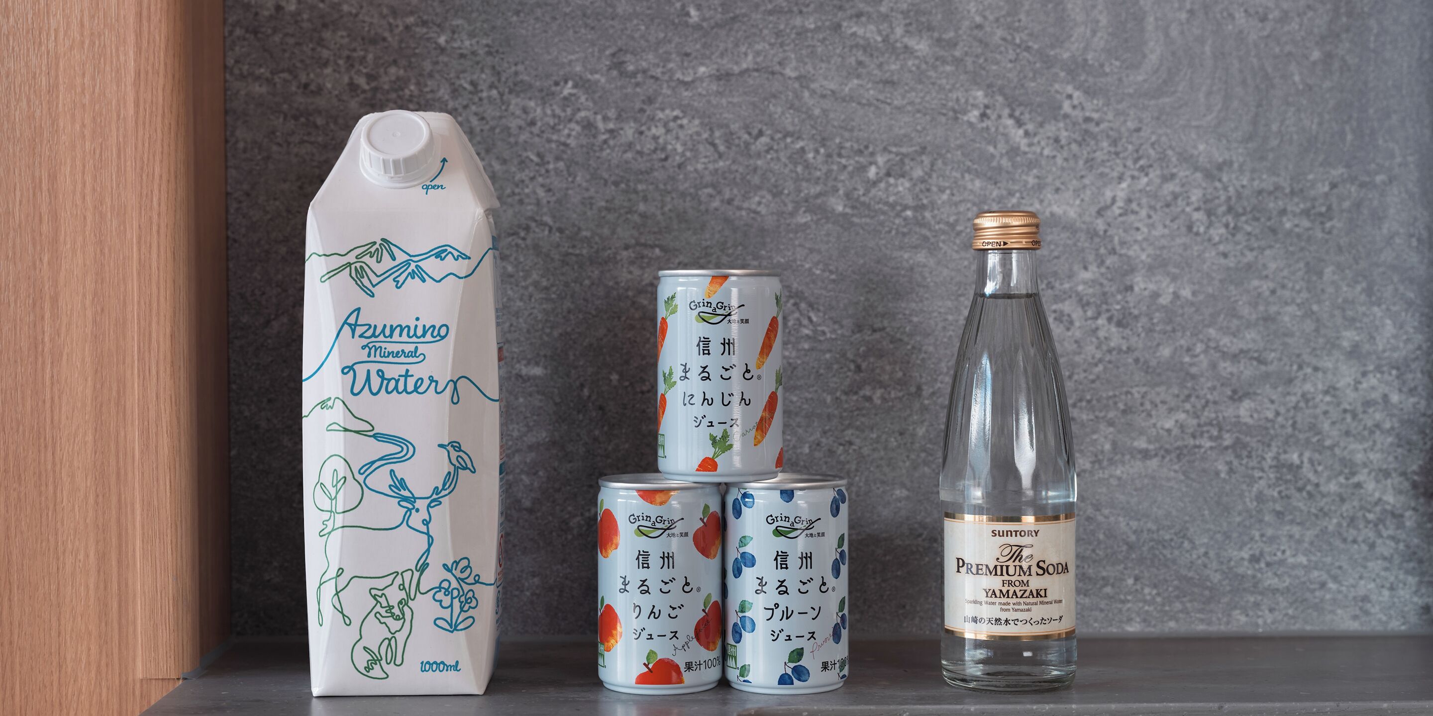 Uma caixa de Azumino Mineral Waters, duas latas de GrinGrin e uma garrafa de Suntory Premium Soda.