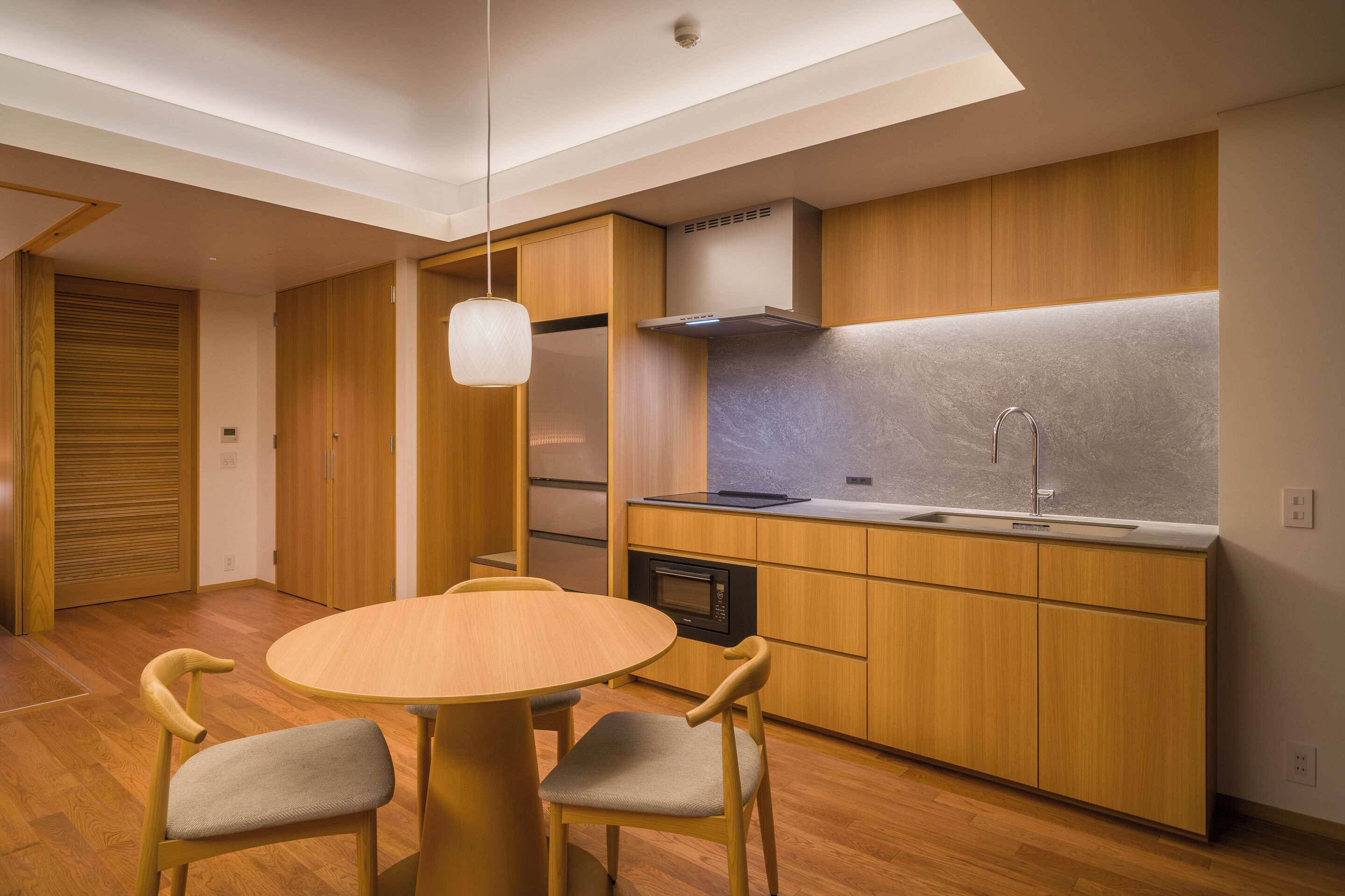 A modern kitchen with wooden cabinets, a round dining table, and two chairs.