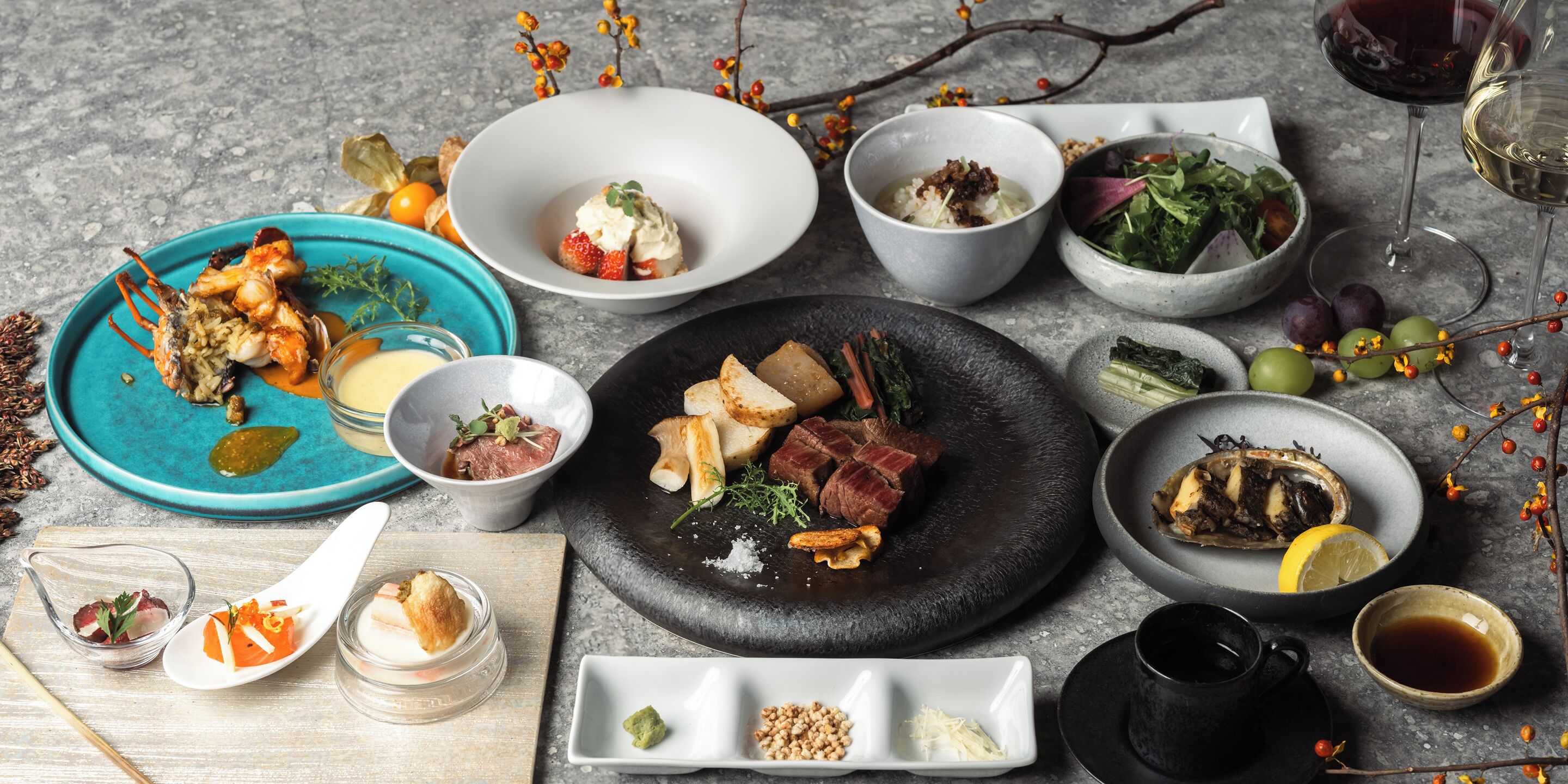 A variety of dishes and drinks on a table, including seafood, meat, and vegetables, with glasses of wine and tea.