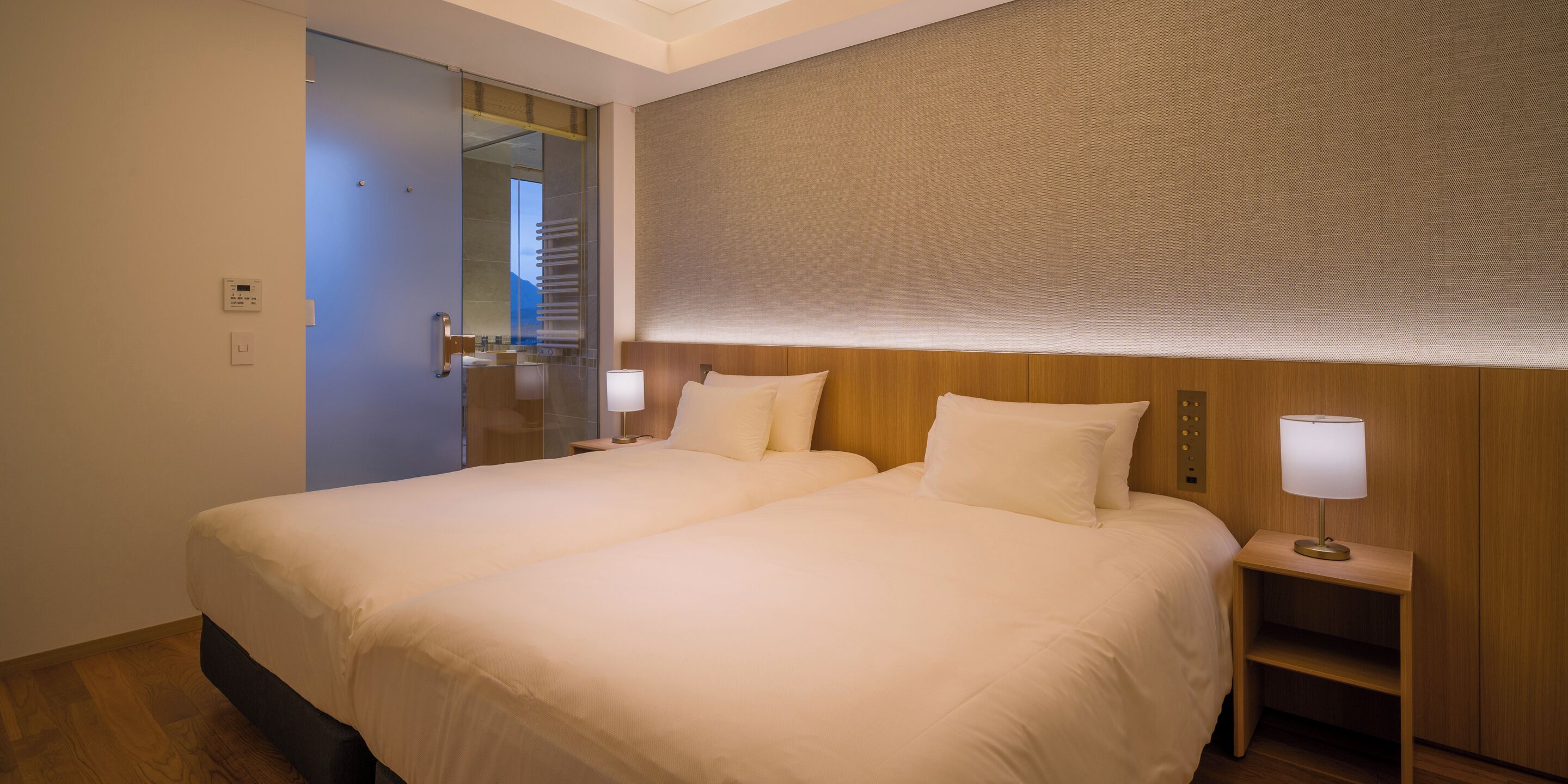 A hotel room with a large bed, bedside tables, and a mirror.