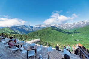 Une terrasse avec des tables et des chaises donnant sur un paysage montagneux.