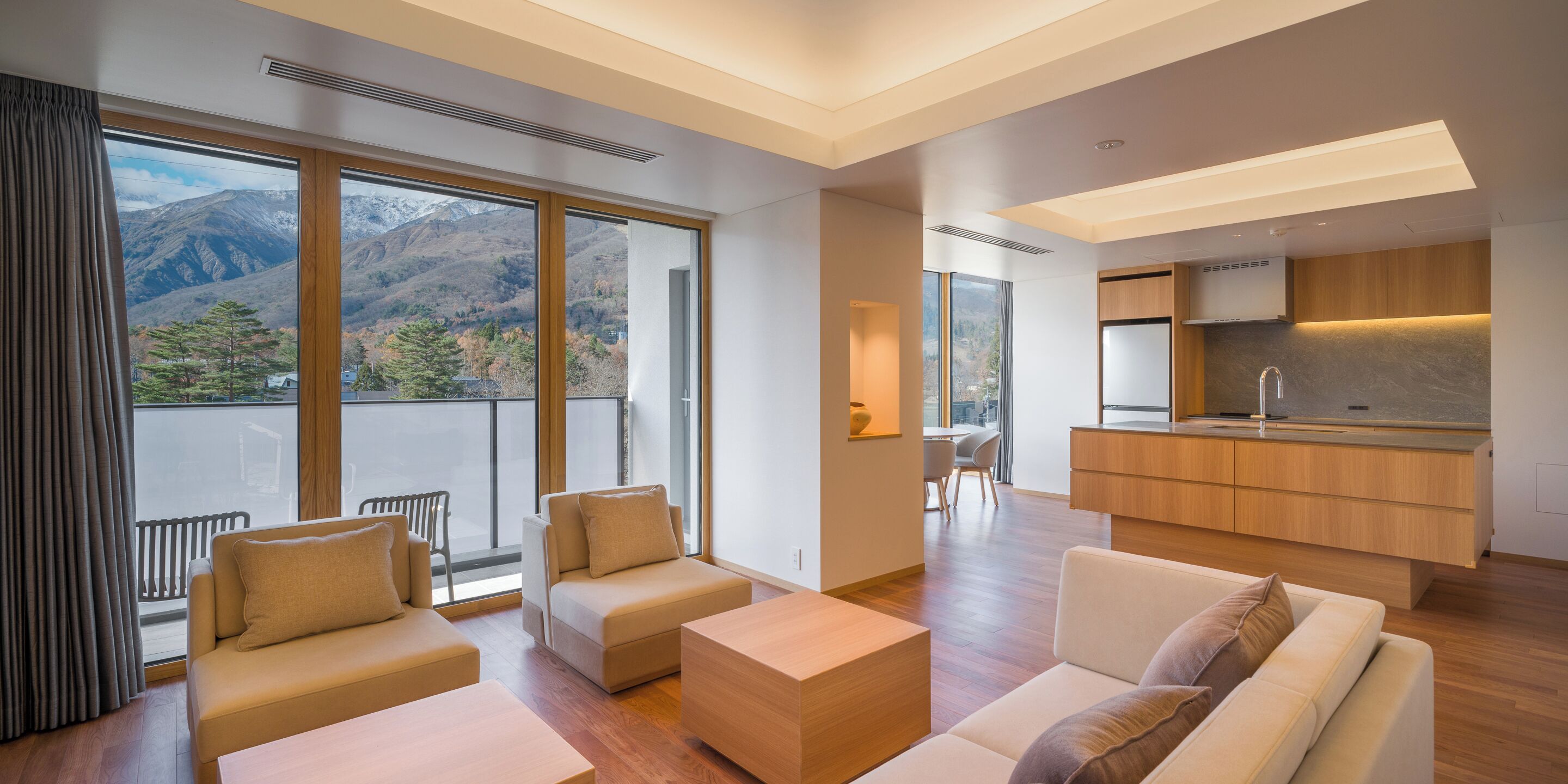 A modern living room with a sofa, a coffee table, and a view of mountains through large windows.