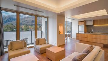 A modern living room with a sofa, a coffee table, and a view of mountains through large windows.
