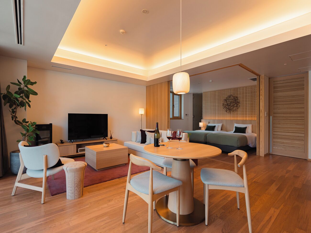 Un salon moderne comprenant un téléviseur à écran plat, une table à manger avec des chaises, un canapé et une table basse.