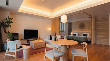 Un salon moderne comprenant un téléviseur à écran plat, une table à manger avec des chaises, un canapé et une table basse.