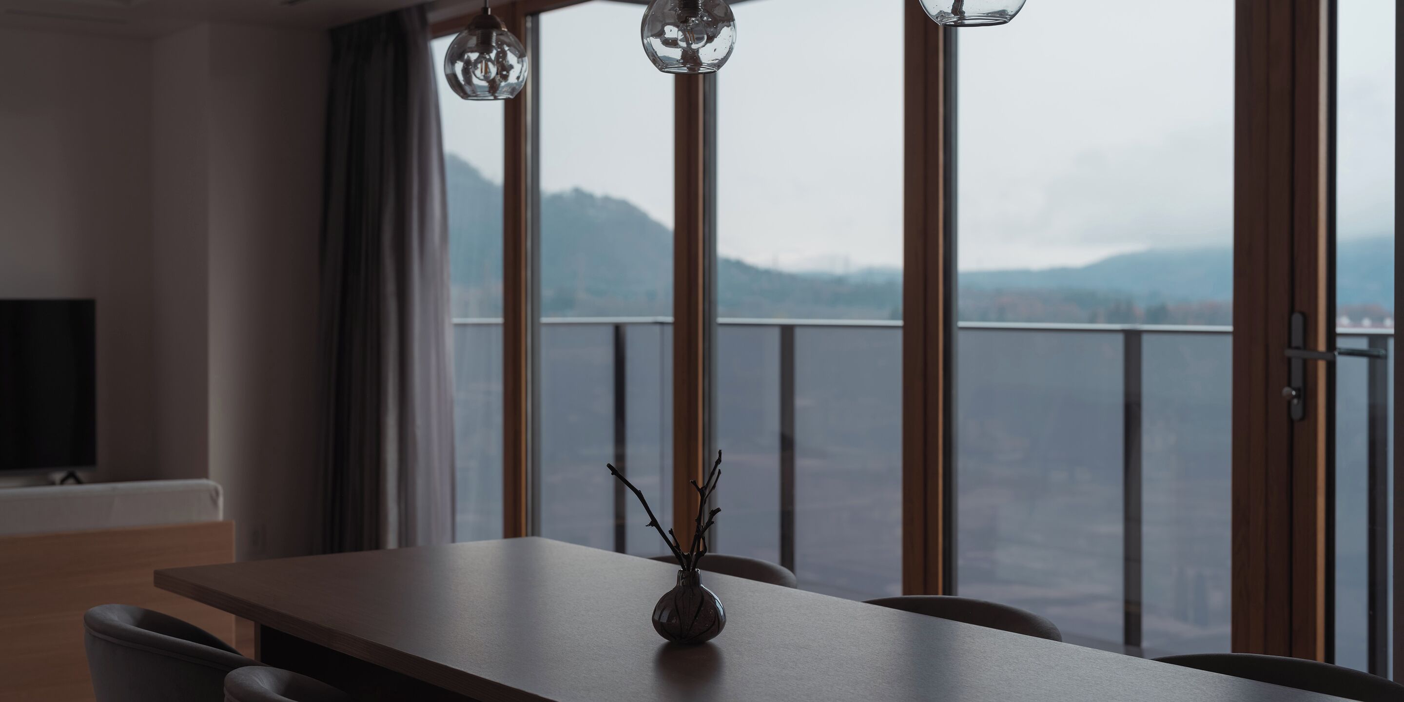 A dining area with a table, chairs, and a vase with branches.