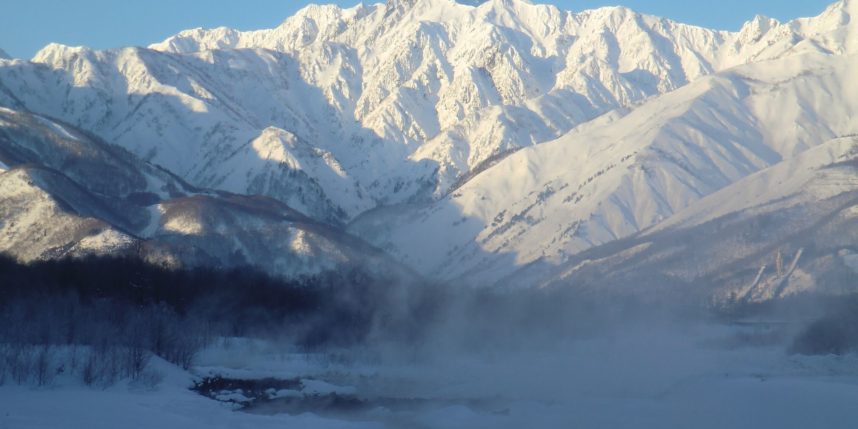 A snow-covered mountain range with a valley in the foreground.